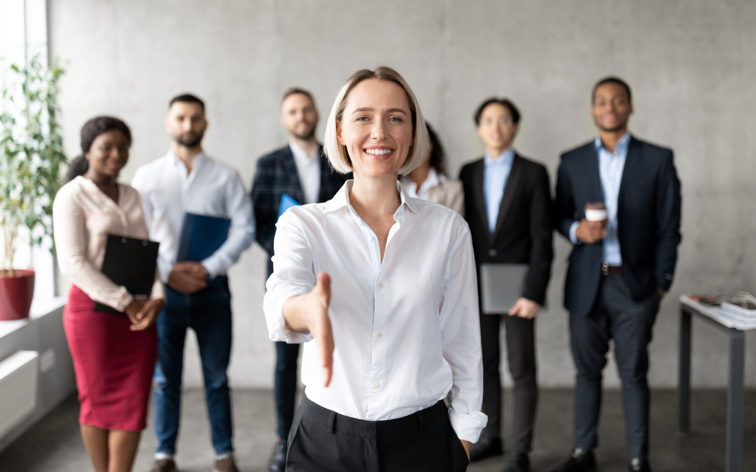 cheerful-businesswoman-stretching-hand-for-handshake-greeting-standing-in-office