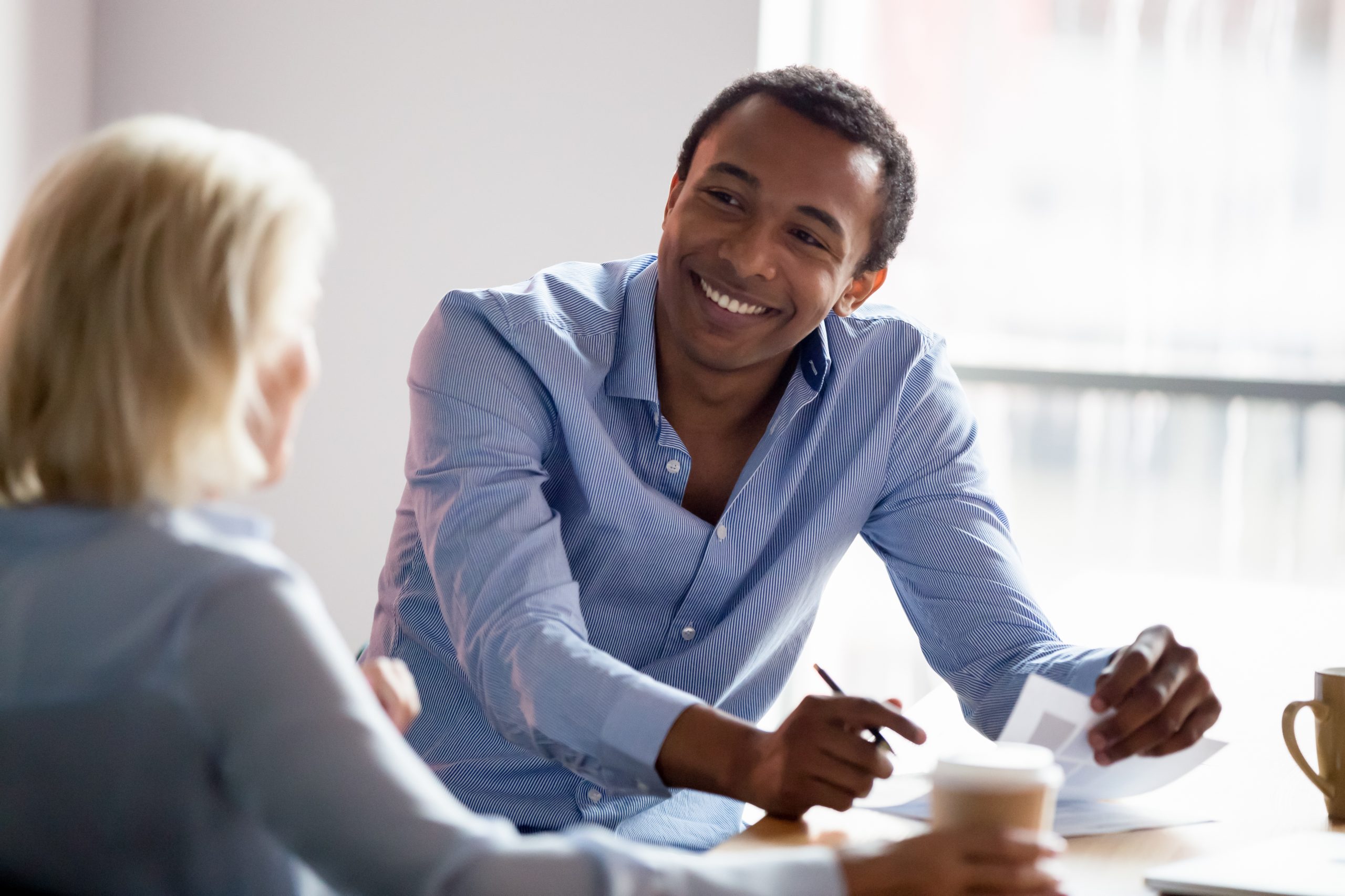 smiling-african-american-manager-talking-with-client-at-business-meeting