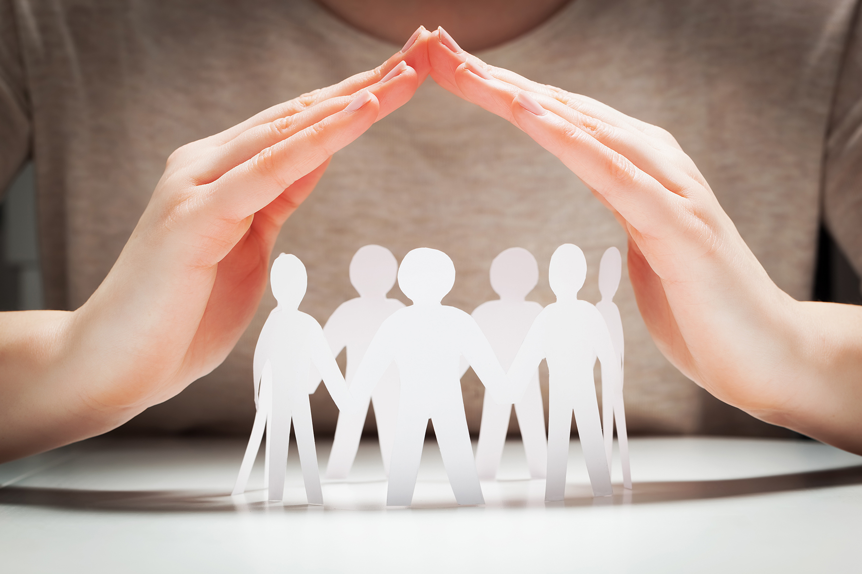 paper-people-under-hands-in-gesture-of-protection-concept-of-insurance